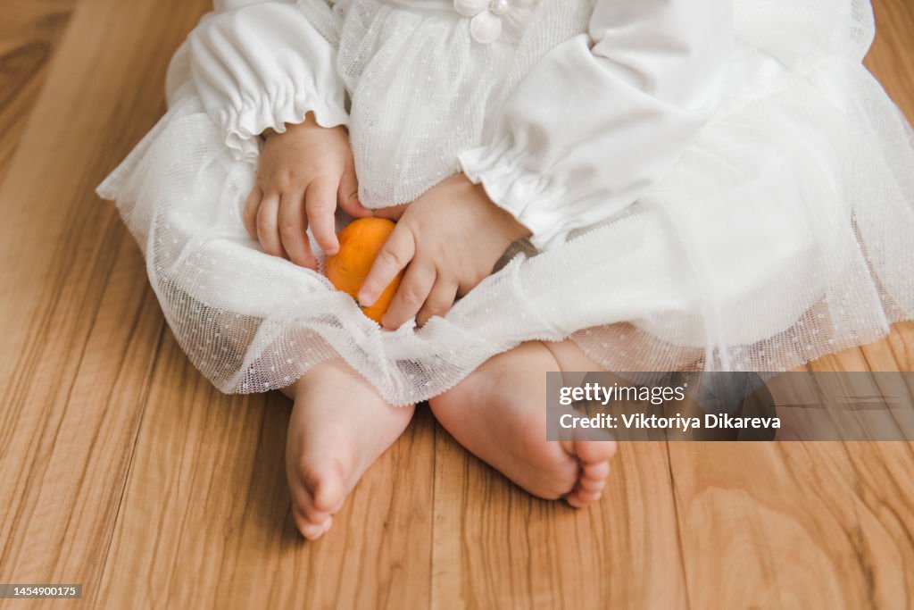 Baby peeling skin off mandarin orange