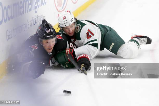 Kyle Okposo of the Buffalo Sabres and Brandon Duhaime of the Minnesota Wild fall to the ice while battling for the puck during the second period of...
