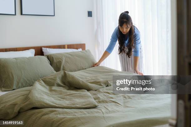 asian woman housewife organizing blankets on the mattress in the bedroom at home. - mattress stock pictures, royalty-free photos & images