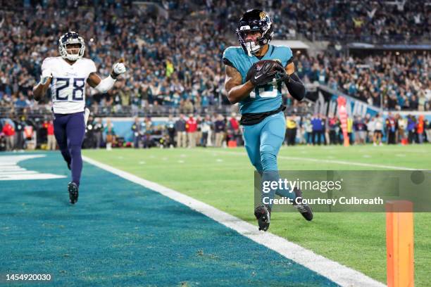 Christian Kirk of the Jacksonville Jaguars runs past Joshua Kalu of the Tennessee Titans while scoring a touchdown during the second quarter at TIAA...