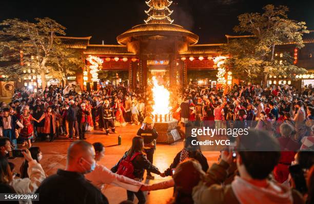Tourists circle around the bonfire at Xiamen Fantawild Dreamland during a lantern show as 2023 Chinese Spring Festival approaches on January 7, 2023...