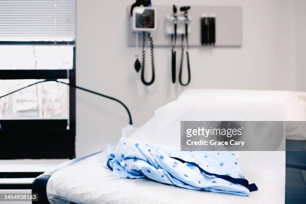 medical gown on examination table in doctor's office - hospital gown imagens e fotografias de stock