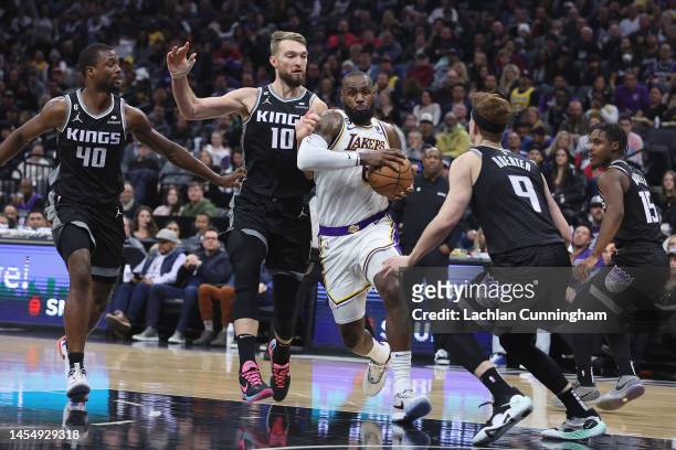 LeBron James of the Los Angeles Lakers drives to the basket against Domantas Sabonis and Kevin Huerter of the Sacramento Kings in the second quarter...