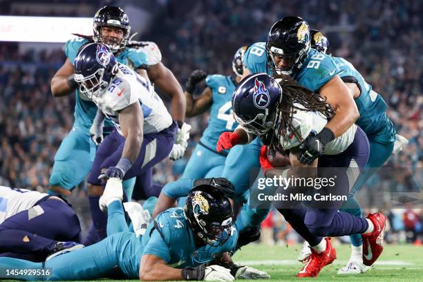 Corey Peters of the Jacksonville Jaguars tackles Derrick Henry of the Tennessee Titans during the fourth quarter at TIAA Bank Field on January 07,...