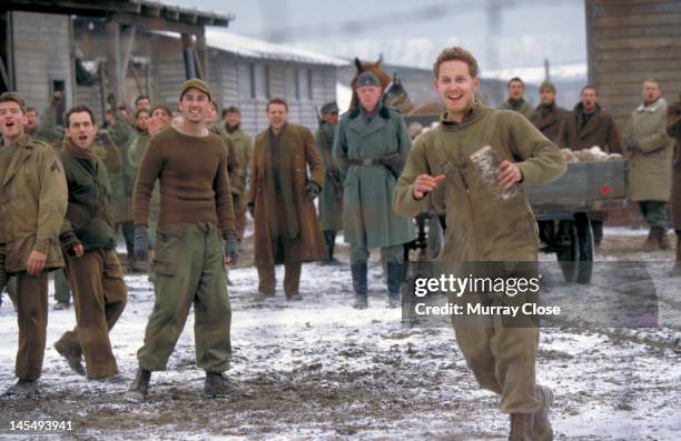 Actor Cole Hauser throwing bread to Russian prisoners-of-war in a scene from the film 'Hart's War', 2002.