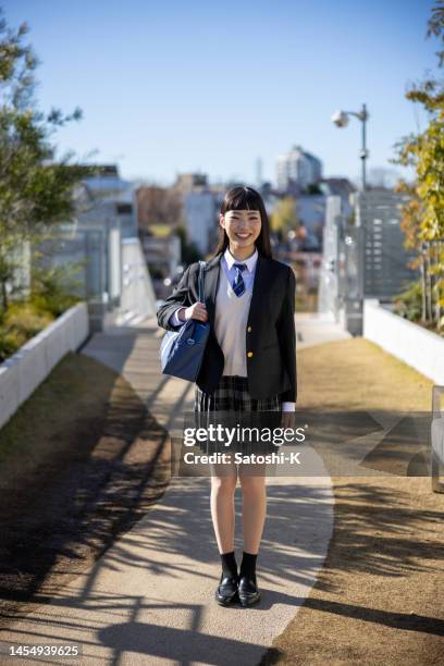 full length portrait of happy high school girl standing in public park - japanese school uniform stock pictures, royalty-free photos & images