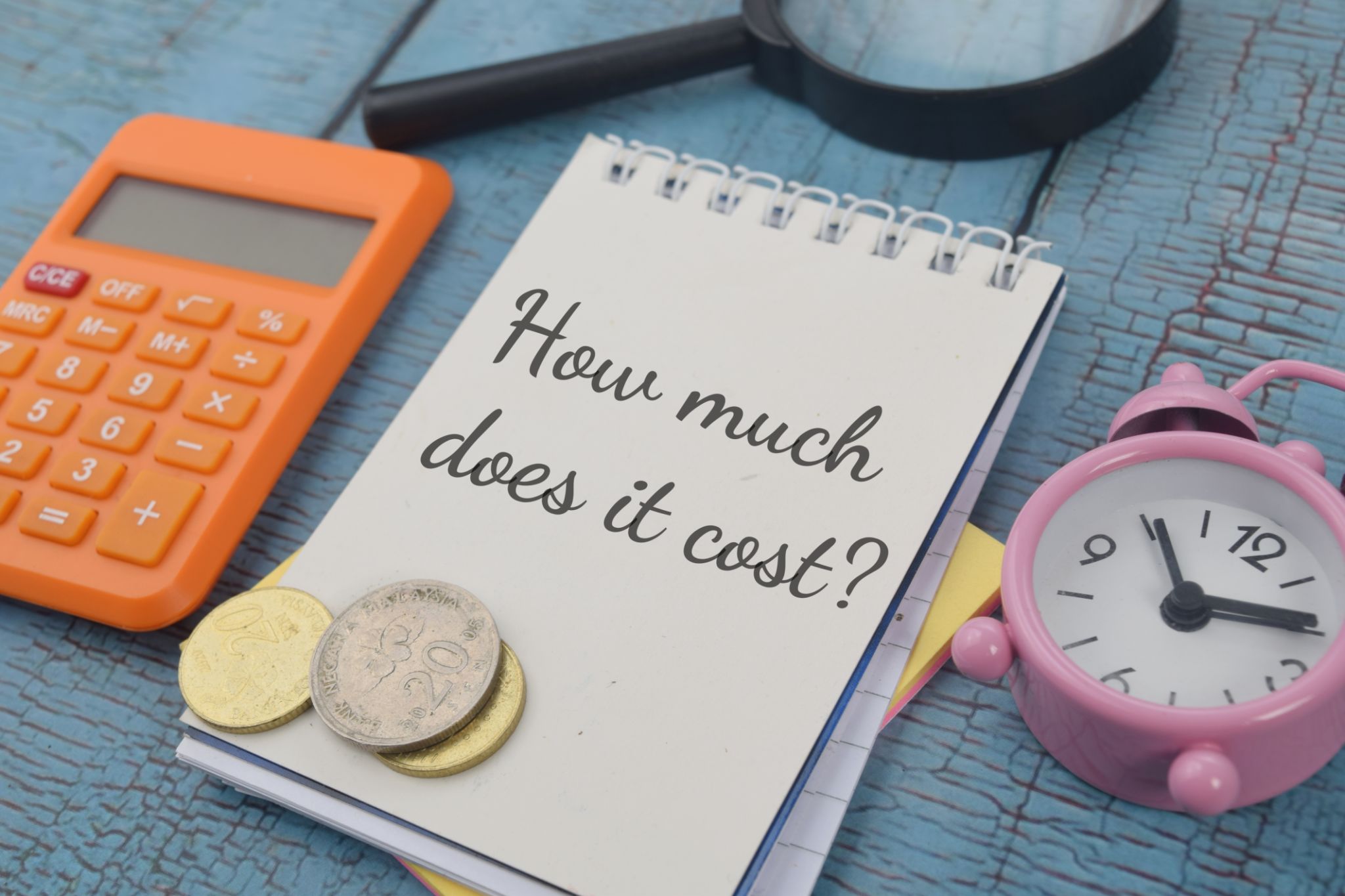 Closeup shot of a white notebook page with the writing how much does it cost Closeup shot of a white notebook page with the writing how much does it cost