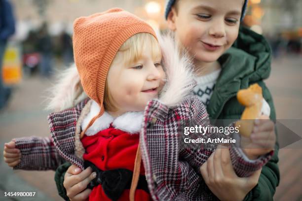 glückliche geschwister mit lebkuchenplätzchen auf dem weihnachtsmarkt - baby spielt mit essen stock-fotos und bilder