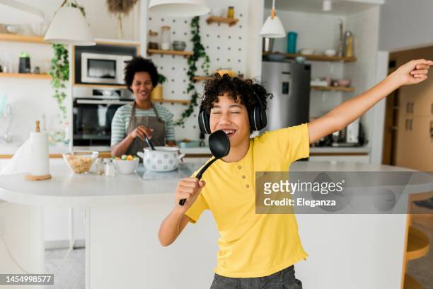 boy having fun while his mother cooking - kid singing stock pictures, royalty-free photos & images