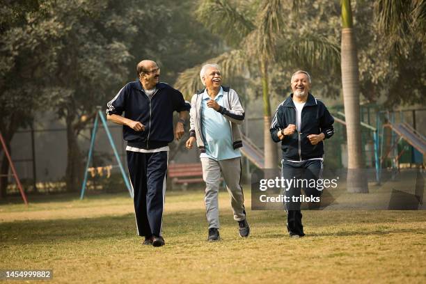 cheerful old men friends running at park - south asia stock pictures, royalty-free photos & images