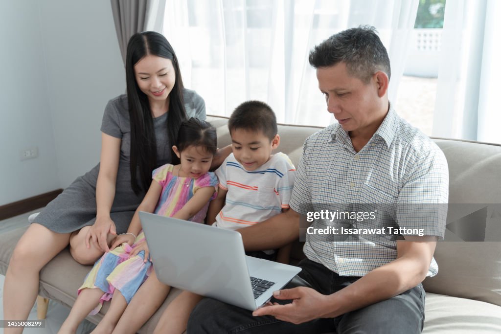 Happy Family Having Fun With Device At Home Parents And Little Children Using Digital Tablet Looking At Screen Sit On Sofa Together Cute Kids Hold Computer Laugh Watch Cartoons Online High-Res Stock Happy Family Having Fun With Device At Home Parents And Little Children Using Digital Tablet Looking At Screen Sit On Sofa Together Cute Kids Hold Computer Laugh Watch Cartoons Online High-Res Stock