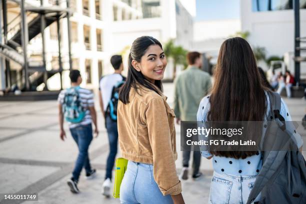 portrait d’une jeune femme marchant avec son amie à l’université - regarder par dessus son épaule photos et images de collection