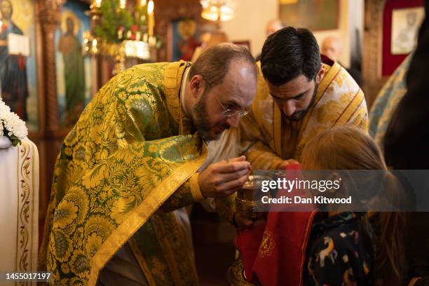 Parishioners and clergy of the Greek Orthodox Church of St Michael the Archangel receive communion after attending a service for the Feast of the...