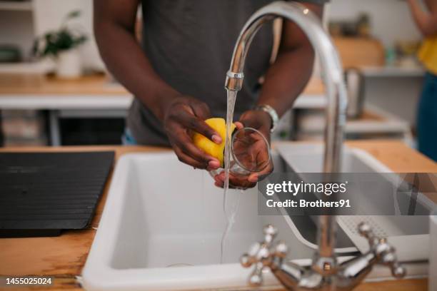 close-up of young man washing a glass in sink at home - dirty dishes stock pictures, royalty-free photos & images