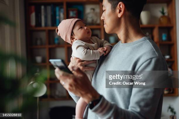asian father taking care of his baby while working from home - baby mobile 個照片及圖片檔