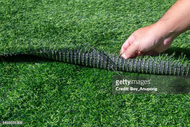 someone hand pulling an artificial turf before replacement. artificial turf is used for covering sport arena or garden. - kunstmatig stockfoto's en -beelden