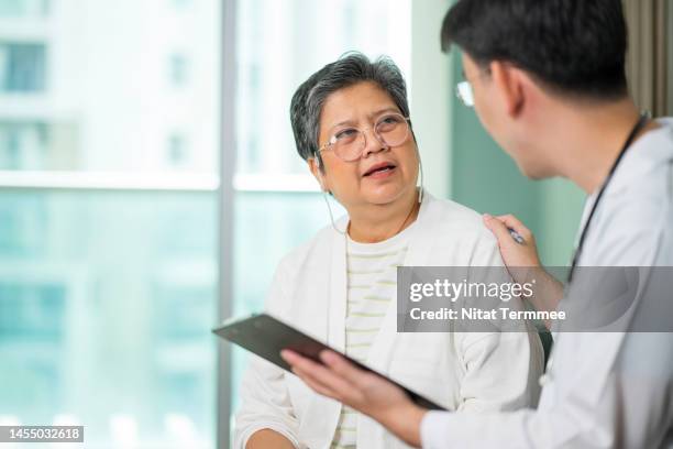 mental health advice from psychologist. an asian elderly patient talking with a male doctor about depressive symptoms in a hospital. - male doctor man patient stock-fotos und bilder