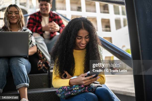 junge frau benutzt handy auf treppen an der uni - student girl using laptop computer and smart phone stock-fotos und bilder