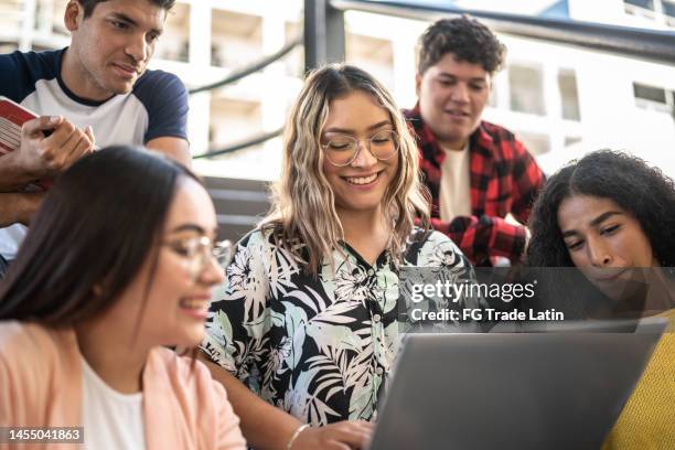 mujer joven mostrando algo en la computadora portátil a sus amigos en las escaleras de la universidad - estudiante fotografías e imágenes de stock