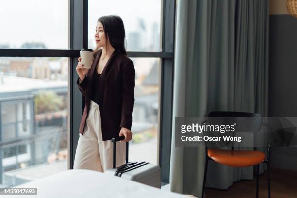 young asian business woman on a business trip arrived in hotel room with suitcase - asian man suite stock-fotos und bilder