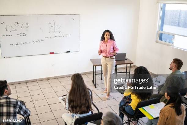 mid adult teacher explaining lesson to university students in the classroom at university - community college campus stock pictures, royalty-free photos & images