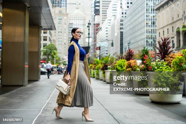 nicely dressed businesswoman seen exiting the building in manhattan after work - businesswoman nyc stock pictures, royalty-free photos & images