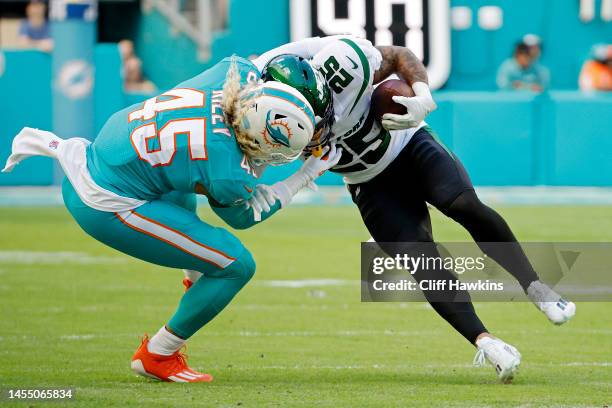 Duke Riley of the Miami Dolphins tackles Ty Johnson of the New York Jets during the first quarter at Hard Rock Stadium on January 08, 2023 in Miami...