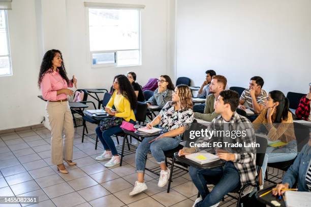 mid adult teacher explaining lesson to her students in the classroom at university - community college campus stock pictures, royalty-free photos & images