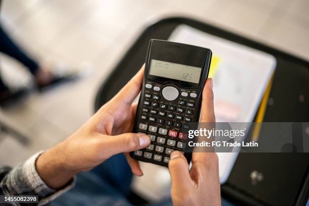 primo piano di uno studente che usa la calcolatrice in classe all'università - moltiplicazione foto e immagini stock