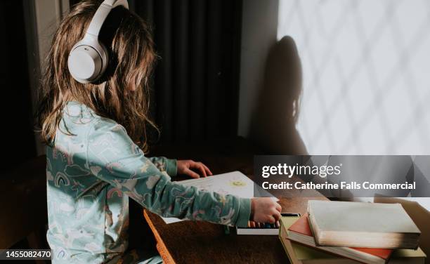 a child wearing large headphones draws with crayons - ear plug ear protectors stock pictures, royalty-free photos & images