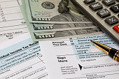 Amount you owe line on income tax return forms, cash money and calculator. Federal tax return, income tax, tax refund and payment concept.