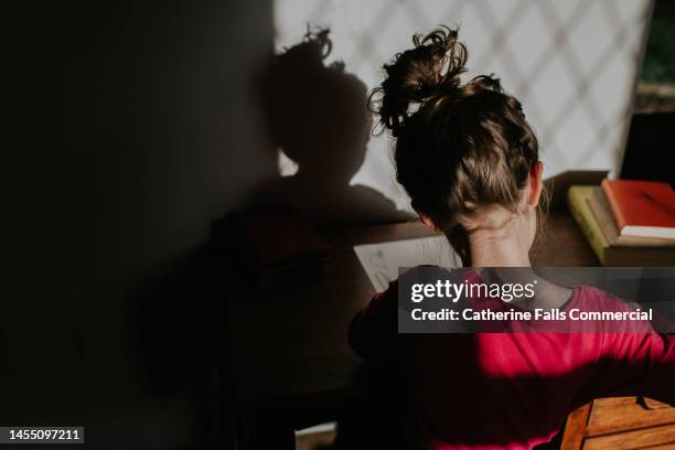 close-up of a child studying at a wooden desk - messy bun stockfoto's en -beelden