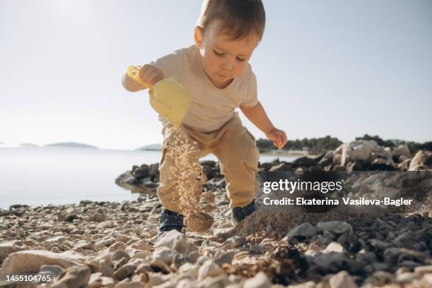 a child on the seashore builds a sand castle - beach bucket stock pictures, royalty-free photos & images