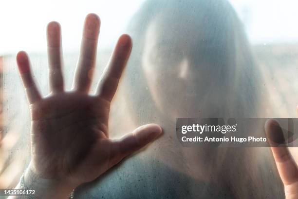 portrait of a blonde woman leaning her hand on fogged glass - woman frog hand stockfoto's en -beelden