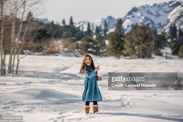 a laughing girl age 7 throws a snow ball - girl wearing boots stock pictures, royalty-free photos & images