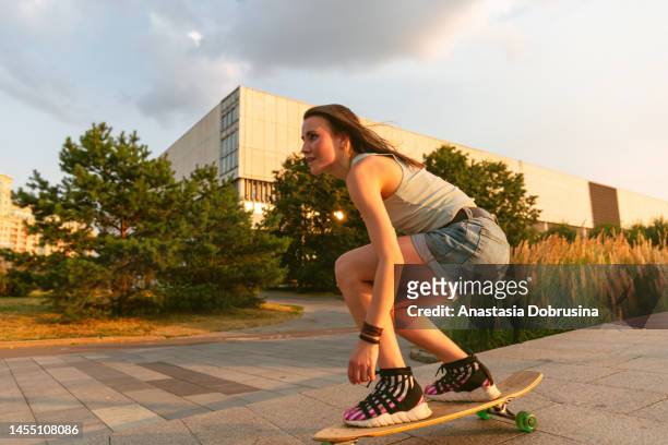 woman rides on longboard at sunset - longboard surfing stock pictures, royalty-free photos & images