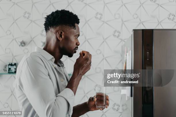 uomo che si medica a casa medicina - prendere-le-pillole foto e immagini stock