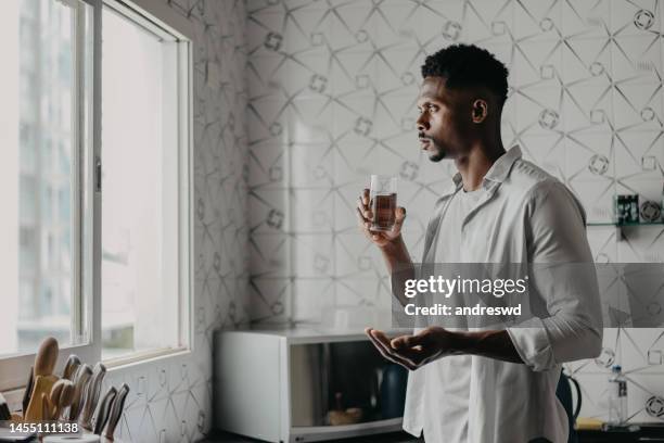 man medicating himself at home medicine - man glasses tablet in kitchen stock pictures, royalty-free photos & images