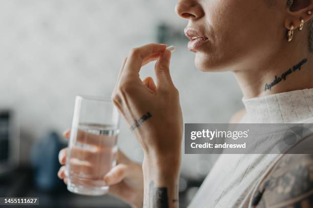 mujer medicándose a sí misma en medicina casera - tomando píldoras fotografías e imágenes de stock
