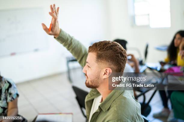 young man making asking a question in the classroom at university - raised hand stock pictures, royalty-free photos & images