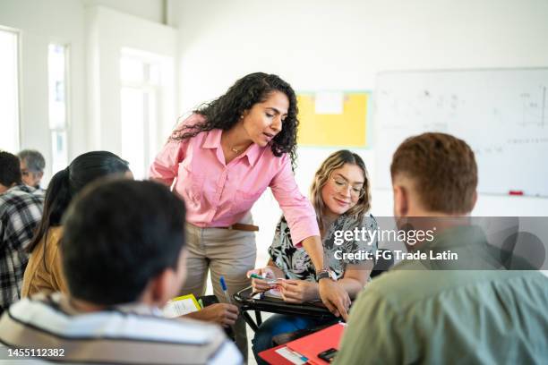 mid adult teacher explaining lesson to university students in the classroom at university - community college stock pictures, royalty-free photos & images