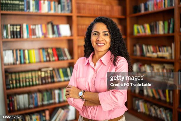 portrait of a mid adult teacher in university library - librarian stock pictures, royalty-free photos & images