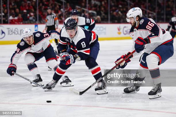 Dmitry Orlov of the Washington Capitals skates with the puck as Cole Sillinger and Kirill Marchenko of the Columbus Blue Jackets defend during the...