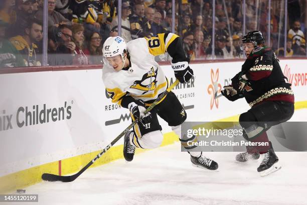 Rickard Rakell of the Pittsburgh Penguins attempts to control the puck ahead of Troy Stecher of the Arizona Coyotes during the first period of the...