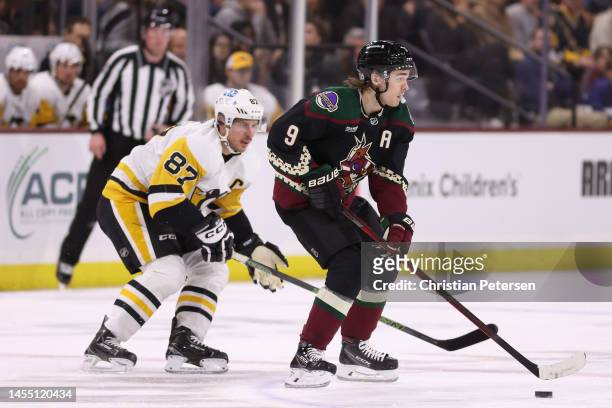 Clayton Keller of the Arizona Coyotes skates with the puck ahead of Sidney Crosby of the Pittsburgh Penguins during the first period of the NHL game...