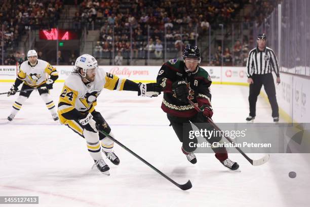 Clayton Keller of the Arizona Coyotes skates with the puck past Ty Smith of the Pittsburgh Penguins during the second period of the NHL game at...