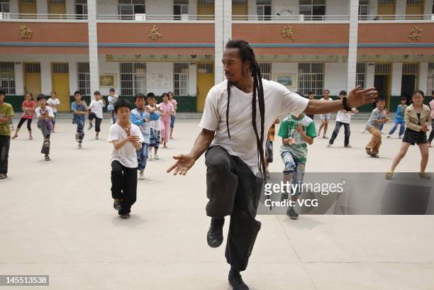 Poet Benjamin Zephaniah and children play T'ai chi ch'uan at Chenjiagou primary school before the June 1 International Children's Day on May 31, 2012...