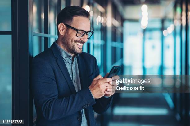 happy businessman looking at his cell phone - stubble stock pictures, royalty-free photos & images