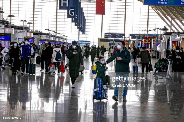 Passengers with suitcases prepare to board an aircraft at Shanghai Pudong International Airport during the Spring Festival travel rush on January 8,...