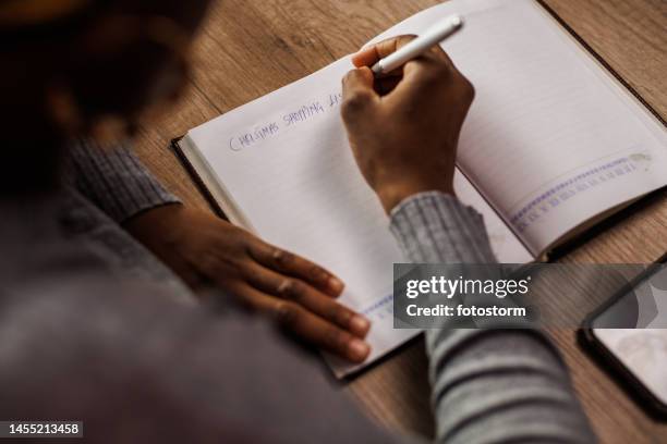 young woman writing a christmas shopping list in a diary - woman shopping list stock pictures, royalty-free photos & images